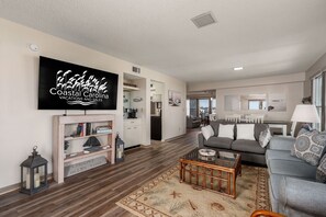 A spacious living room with a flat-screen TV, a coffee bar, and a sofa.