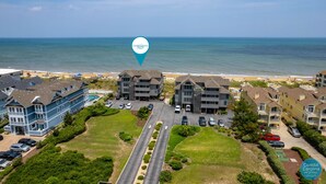 An aerial view of Coastal Carolina Vacation's residential complex with a beach view, multiple buildings, and a parking area. - Carolina Ocean Views: Dog Friendly, Ocean Views (Kill Devil Hills)
