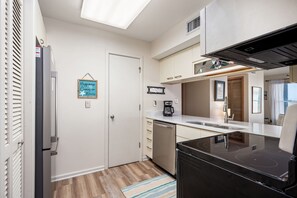 A compact kitchen with a refrigerator, a coffee maker, and a dishwasher.