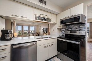 A modern kitchen with a built-in dishwasher, a microwave, and a stove. - Carolina Ocean Views: Dog Friendly, Ocean Views (Kill Devil Hills)