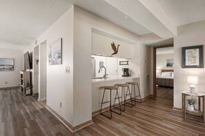 A hotel room with a kitchenette, a bed, a bathroom, and a hallway. - Carolina Ocean Views: Dog Friendly, Ocean Views (Kill Devil Hills)