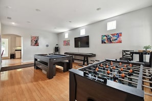 A room with a pool table, foosball table, and a television. - Private Tampa House · Game Room · Sleeps 12 (Tampa)