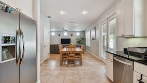 A modern kitchen with a built-in refrigerator, a dining area with a wooden table and chairs, and a kitchen island with a sink.