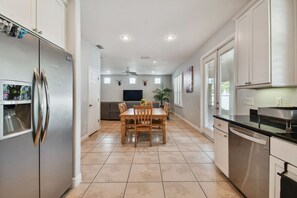 A modern kitchen with a built-in refrigerator, a dining area with a wooden table and chairs, and a kitchen island with a sink.