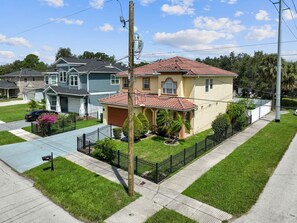A residential house with a red-tiled roof, a front yard with a black fence, and a mailbox. - Game Room House, Sleeps 12, Near Everything Tampa (Tampa)