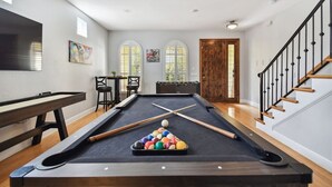 A pool table with balls, a billiard cue, and a pool table with a wooden bench.