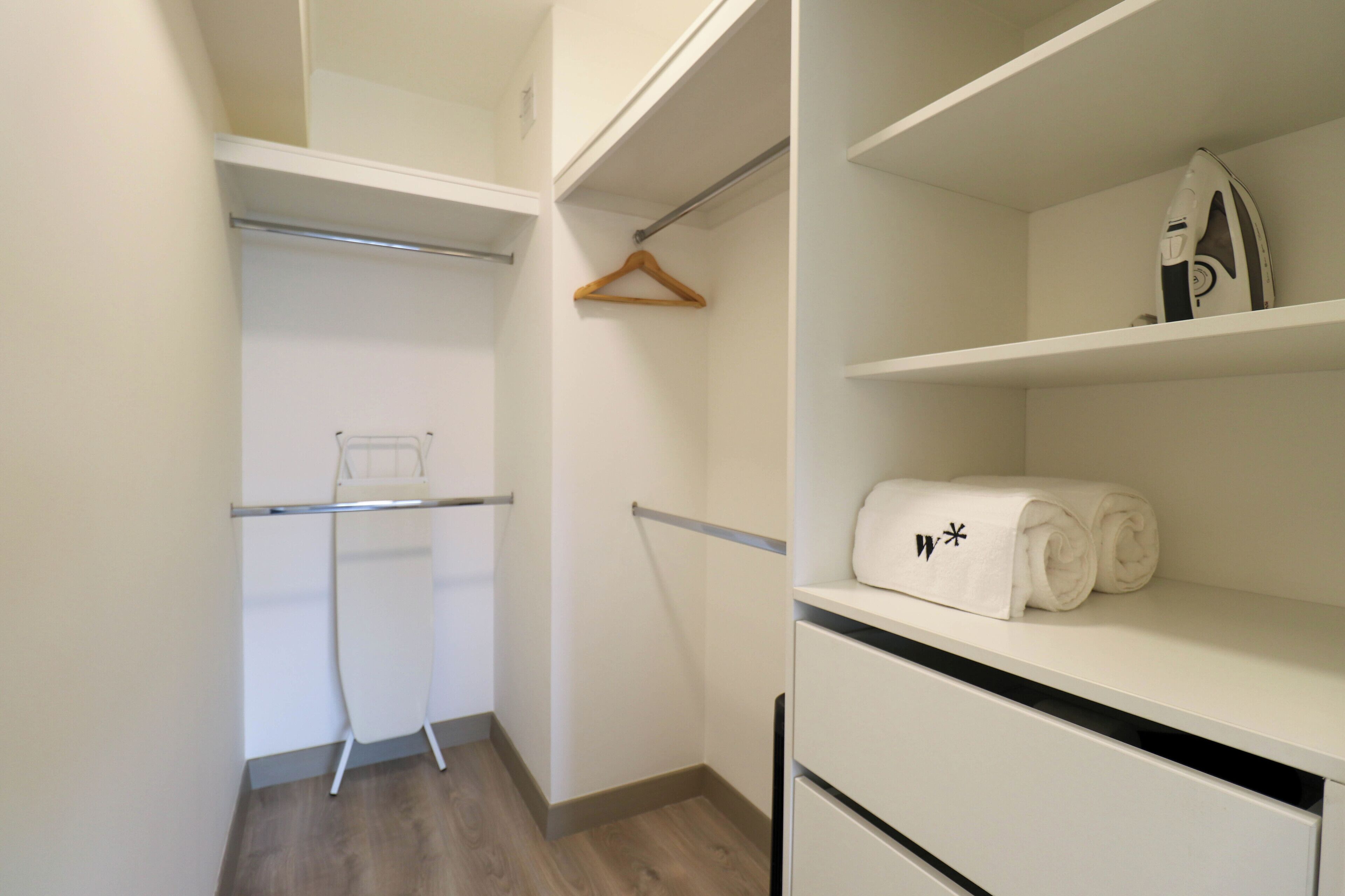 Um closet amplo com espaço para pendurar roupas, prateleiras e uma toalha dobrada na prateleira superior.