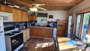 A kitchen with wooden cabinets, a stove, a microwave, and a ceiling fan. - Relaxing rustic cabin on the lake 25 feet from the shore. (Baileyville)