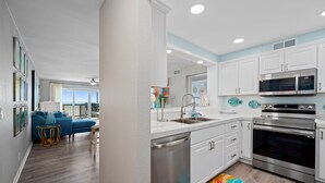A modern kitchen with white cabinets, stainless steel appliances, and a colorful rug.