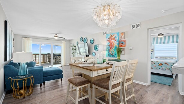 A dining area with a wooden table, white chairs, and a chandelier.
