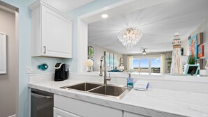 A modern kitchen with a double sink, white cabinetry, and a marble countertop.