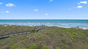 A coastal landscape with a wooden boardwalk leading to the beach.