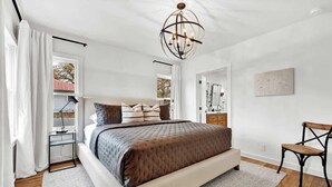 A modern bedroom with a large bed, a desk, and a chair.