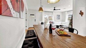 A modern dining area with a wooden table, benches, and a fruit tray.