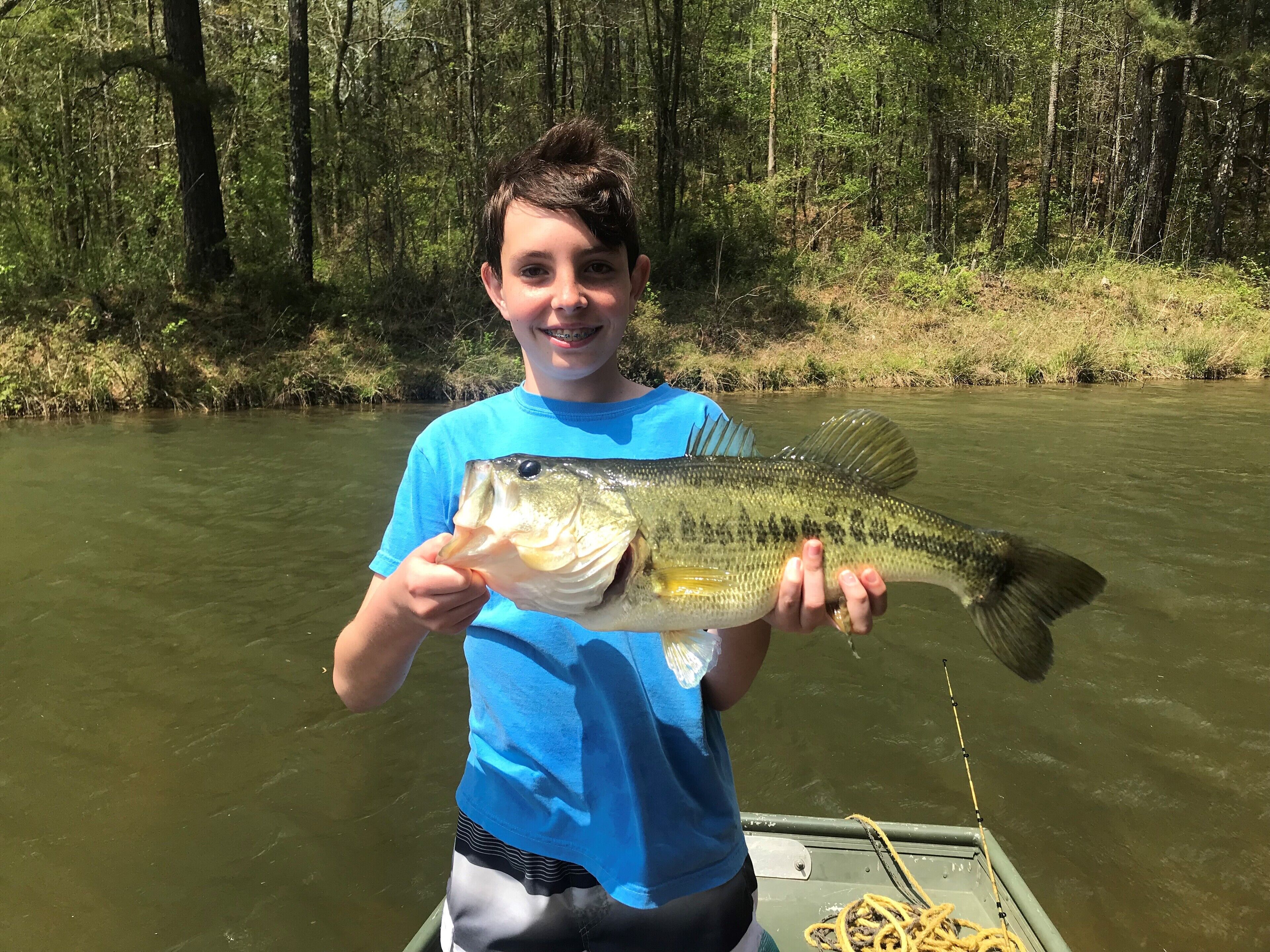 A person holding a fish by a river.