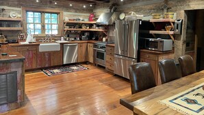 Una cocina rústica con armarios de madera, un refrigerador de acero inoxidable y un comedor con una mesa y sillas.