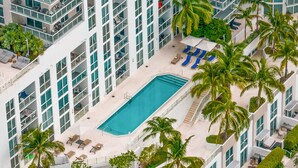 A high-rise hotel with a rooftop pool surrounded by palm trees and sun loungers. - Ocean view Amazing 3BR at Tiffany House (Fort Lauderdale)