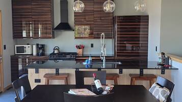 A modern kitchen with dark wood cabinets, a central island, and pendant lighting.