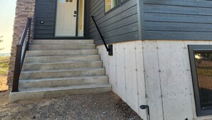 Una casa moderna de dos pisos con un muro de acento de piedra, una puerta principal y un conjunto de escalones de hormigón que conducen a la entrada.