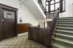 Un escalier avec une rampe en bois et une moquette à motifs.