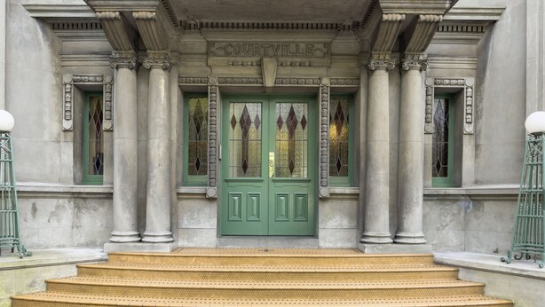 A building with a green double door, columns, and a sign reading "COURTVILLE". - Heritage Apartment on City Fringe (Auckland)
