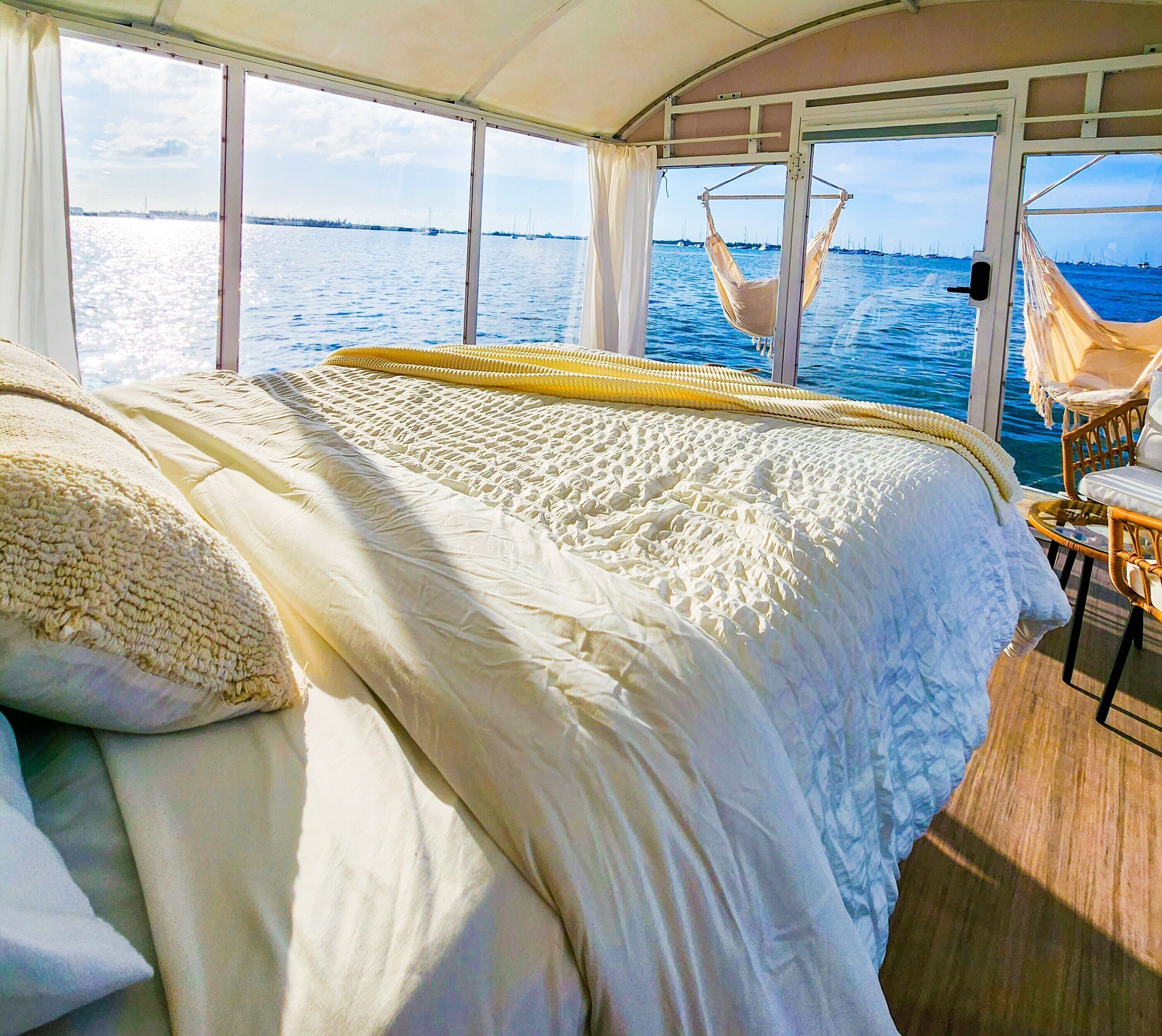 Une chambre avec un grand lit, un fauteuil suspendu et une vue sur la mer.