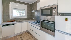 A modern kitchen with a gas stove, oven, microwave, and built-in refrigerator. - Vacay L’Escala - Casa Los Pinos, pool and tranquility (l'Escala)