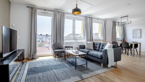A modern living room with a sofa, TV, and dining area. - Lovely Mariahilf 2BR w/ Elevator, nr Shops & Cafes, by Blueground (Vienna)