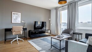 A modern living room with a flat-screen TV, a leather chair, a sofa, and a coffee table. - Lovely Mariahilf 2BR w/ Elevator, nr Shops & Cafes, by Blueground (Vienna)