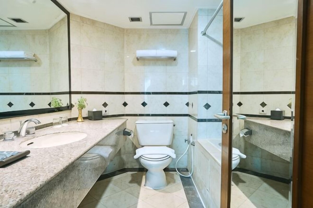 A bathroom with a marble sink, toilet, and a glass shower enclosure.