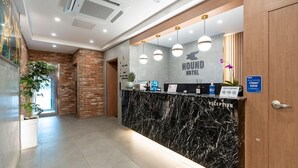 A reception area with a marble counter, a sign for Hound Hotel, and a 'Clean Zone' sign. - Jecheon Hound Hotel (Jecheon)