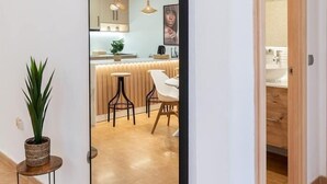 Eine moderne Küche mit Kochinsel, Pendelleuchten und Blick ins Badezimmer.