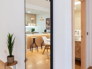 A modern kitchen with a central island, pendant lighting, and a view into a bathroom.