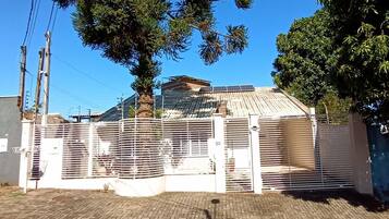 A gated property with a paved entrance, a palm tree, and a building with solar panels.