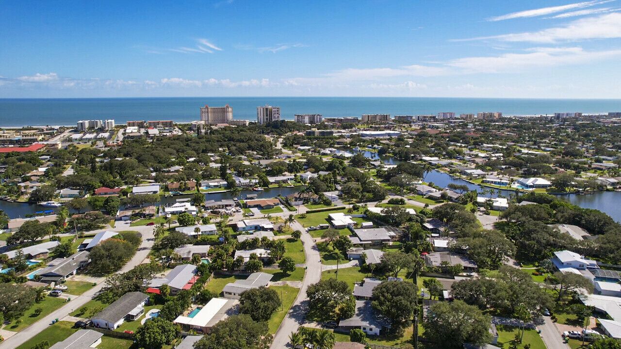 Vista aérea de uma área residencial costeira com casas, ruas e um porto de iates.
