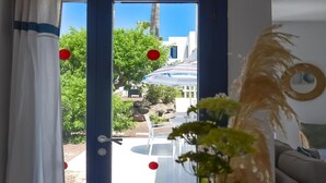 Habitación con vista a un jardín, un sofá blanco y una planta decorativa.