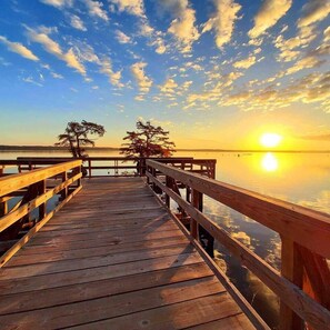 A wooden pier extending over calm water with a sunset in the background. - The Tackle Box at Reelfoot (Hornbeak)