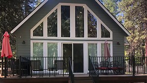 Una casa de dos pisos con un balcón, ventanas grandes y una escalera que conduce a la entrada.
