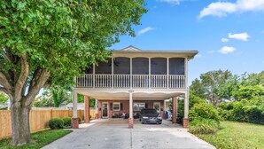 A two-story house with a covered porch, a driveway, and a tree in the foreground. - Stylish 1BR Apartment in Cape May (Cape May)