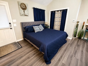 Een slaapkamer met een bed, een deur, een wereldbol aan de muur en een raam met gordijnen.