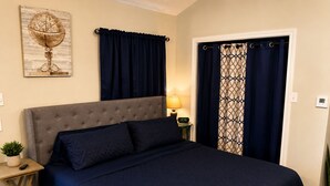 A bedroom with a bed, a nightstand, a lamp, a globe artwork, and curtains. - Quiet Farm Guesthouse Near Lake Houston (Crosby)