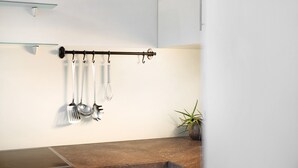 A kitchen with a utensil rack, a potted plant, and a modern design.