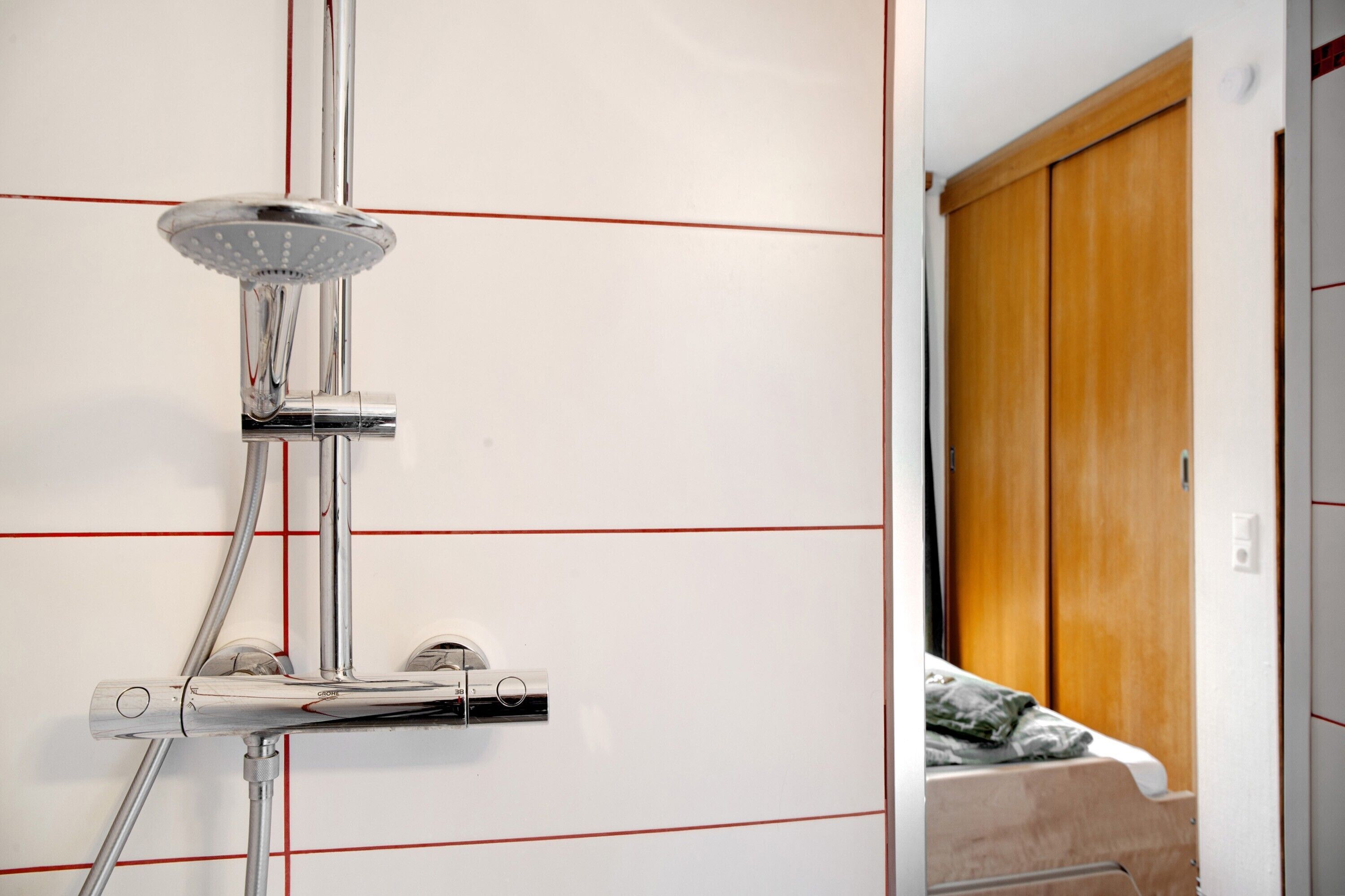 Ein Badezimmer mit Dusche, einem Bett und einem Holzschrank.