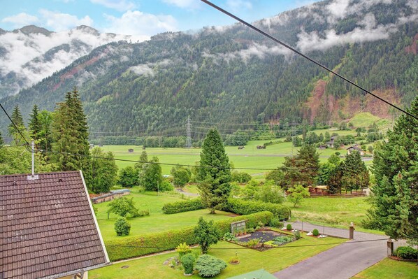 Zona residencial con una casa, un jardín y una montaña al fondo.