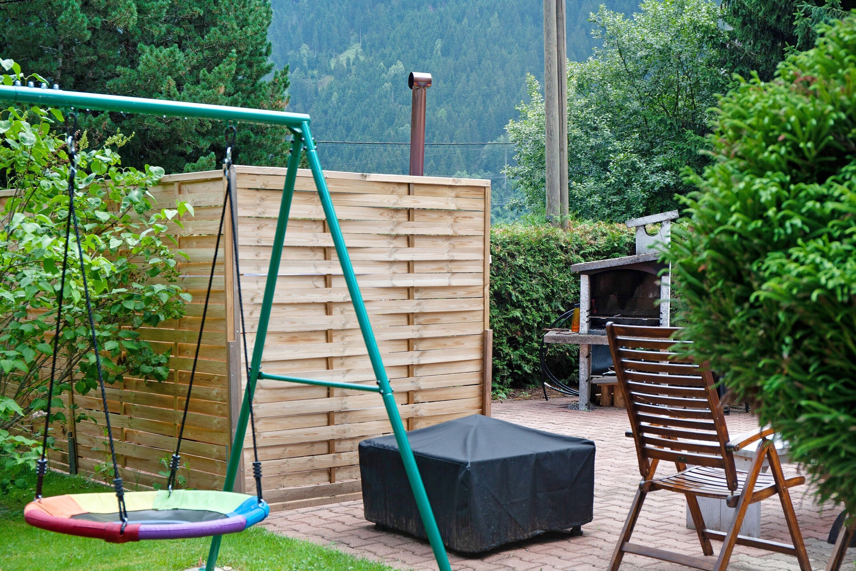 Eine Terrasse mit Schaukel, überdachter Sitzgelegenheit und Holzzaun.