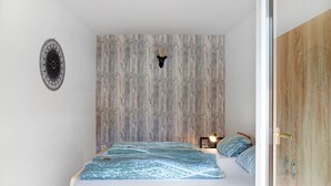 A bedroom with a bed, a wooden headboard, a wall-mounted deer head, and a circular wall decoration. - Apartment "Flying Hirsch" at Molltaler Appartements with Mountain View, Balcony & Wi-Fi (Stall)