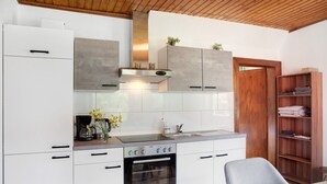 A modern kitchen with white cabinets, a built-in oven, and a wooden door. - Apartment "Flying Hirsch" at Molltaler Appartements with Mountain View, Balcony & Wi-Fi (Stall)