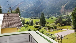 A residential area with a house, green lawns, trees, and mountains in the background. - Apartment "Flying Hirsch" at Molltaler Appartements with Mountain View, Balcony & Wi-Fi (Stall)
