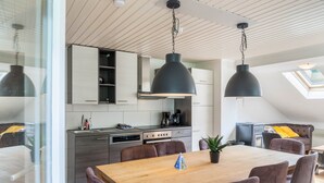 Una cocina moderna con comedor, que incluye una mesa y sillas de madera, y un entrepiso con cama y vistas.