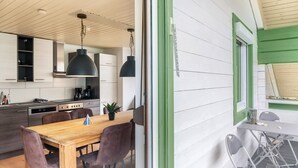 Una cocina moderna con armarios de madera, una mesa de comedor con sillas e iluminación colgante.